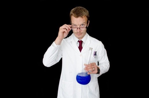 Ein junger Mann mit einem Glasbehälter mit blauer Flüssigkeit als Symbol.