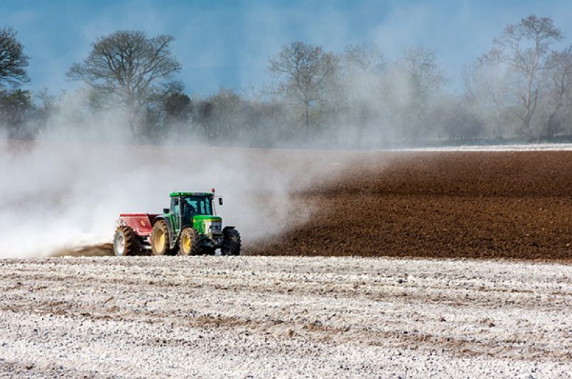 Symbolbild: Ein Traktor bringt auf einem Feld Dünger aus.