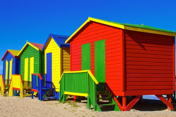 Bunte Holzhäuser an einem Strand.