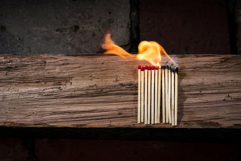 Brennende Streichhölzer auf einem Holzbalken.