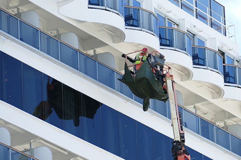 Ein Kreuzfahrtschiff wird von außen mit Hochdruck gereinigt.